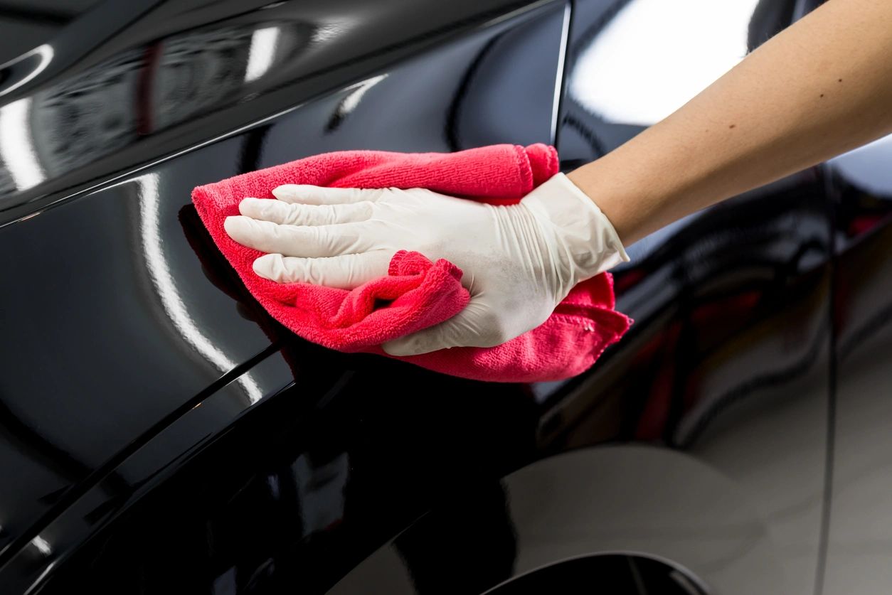 Microfiber towel drying the wet black paint of a vehicle panel